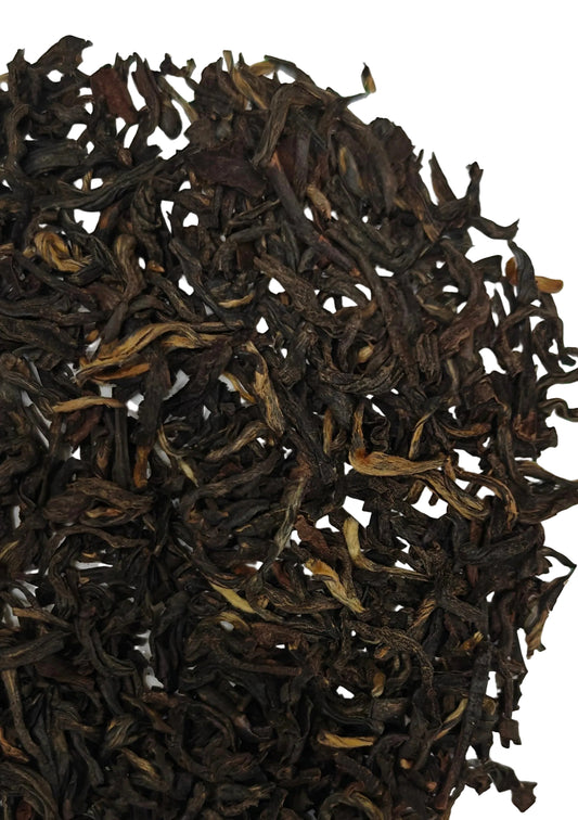 Close-up of dark brown tea leaves on a white background